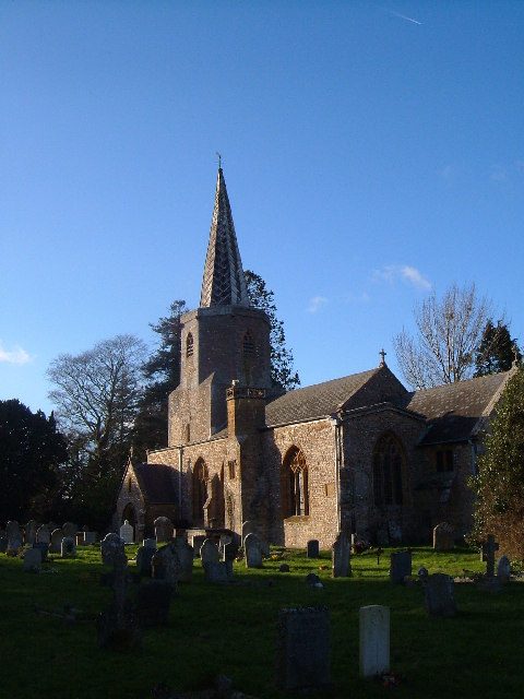 The tower and lead spire of the church in low winter sunlight, seen from the churchyard